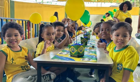 Crianças reunidas à mesa decorada para a campanha da Copa